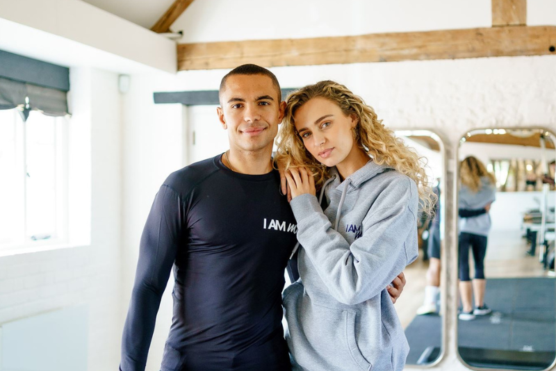 A couple wearing gym wear, the woman with her hand over the mans shoulders 